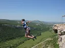 Lex Tarrel прыгает со скалы на веревке над зеленой долиной в Крыму, 2011 год, снимок в момент прыжка