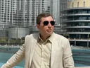 Lex Tarrel в Дубае в светлом пиджаке и темных очках на балконе, 2021 год, за спиной небоскребы